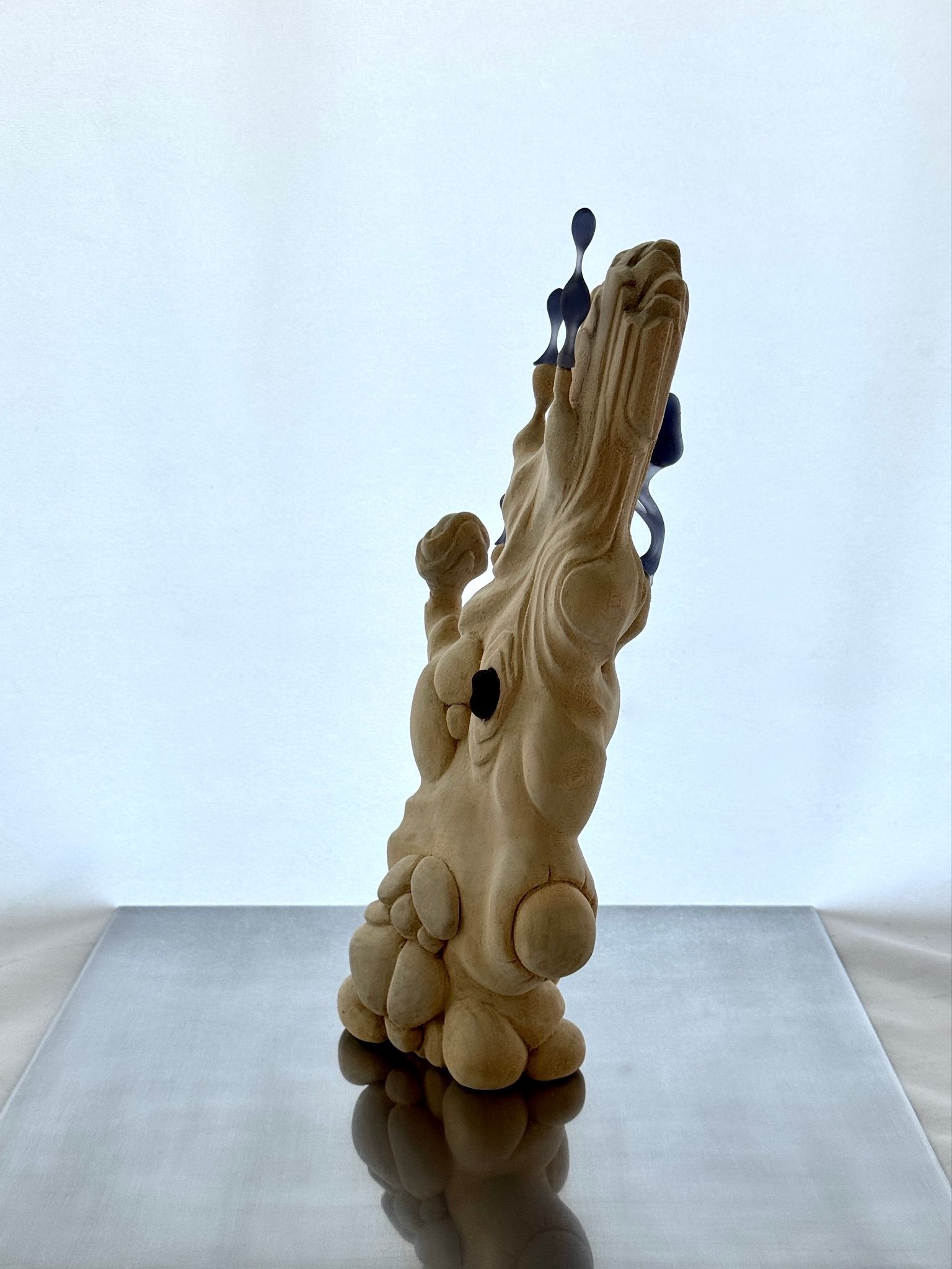 Lifeform, a carved basswood sculpture with rounded forms and dark blue resin inclusions, standing upright.